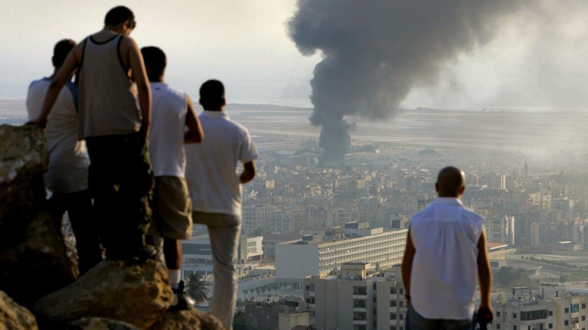 Lebanese youths gather in July 2006, during Israel’s last war with Hezbollah, to watch smoke billowing after an Israeli airstrike at Beirut International Airport.