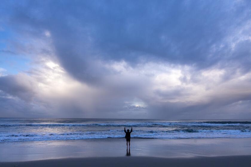 Santa Monica, CA - March 31: A man exercises in the surf as a late season storm moves out of Southern California on Sunday, March 31, 2024 in Santa Monica, CA. (Brian van der Brug / Los Angeles Times)