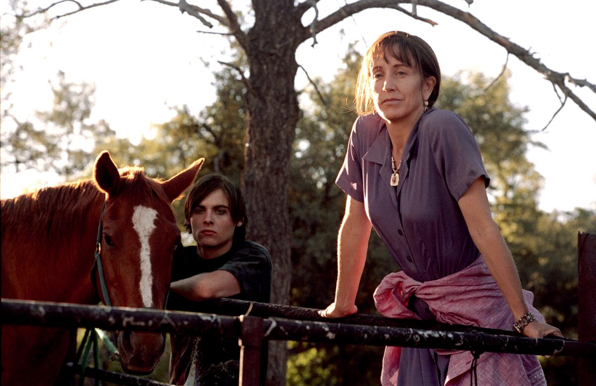 A young man stands near a horse while a woman steps up on the fence in "Transamerica." 