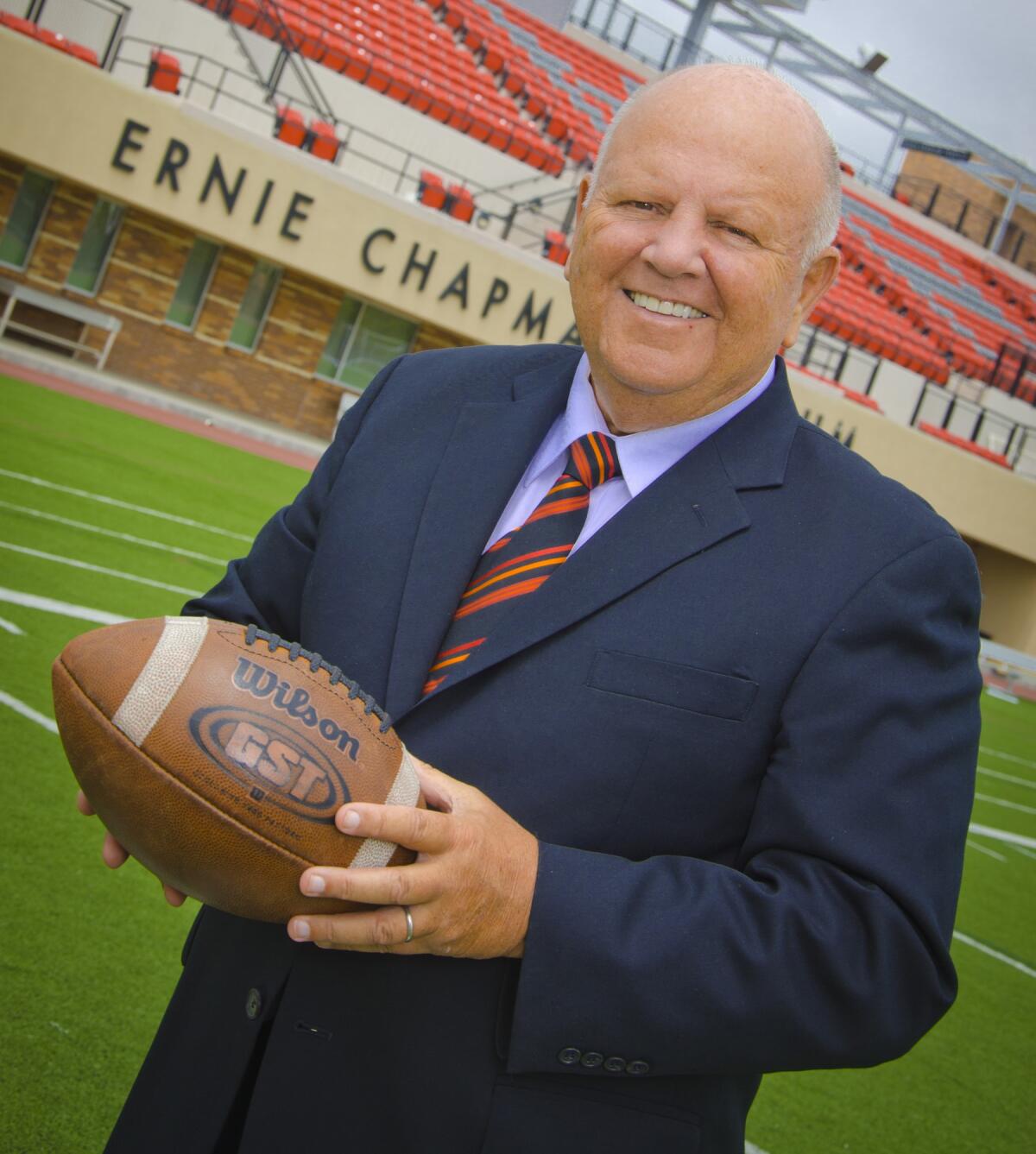Longtime Chapman Universtiy athletic director Dave Currey holds a football while standing on the school's football field.