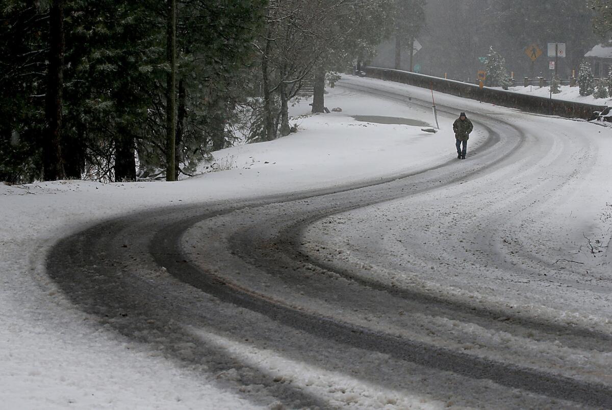 Running Springs resident Sean Benton walks along Holiday Lane as snow flurries hit the area Thursday.