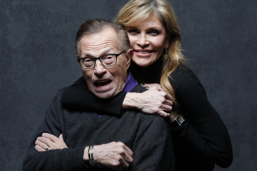 Shawn King stands behind Larry King, hugging him around the neck