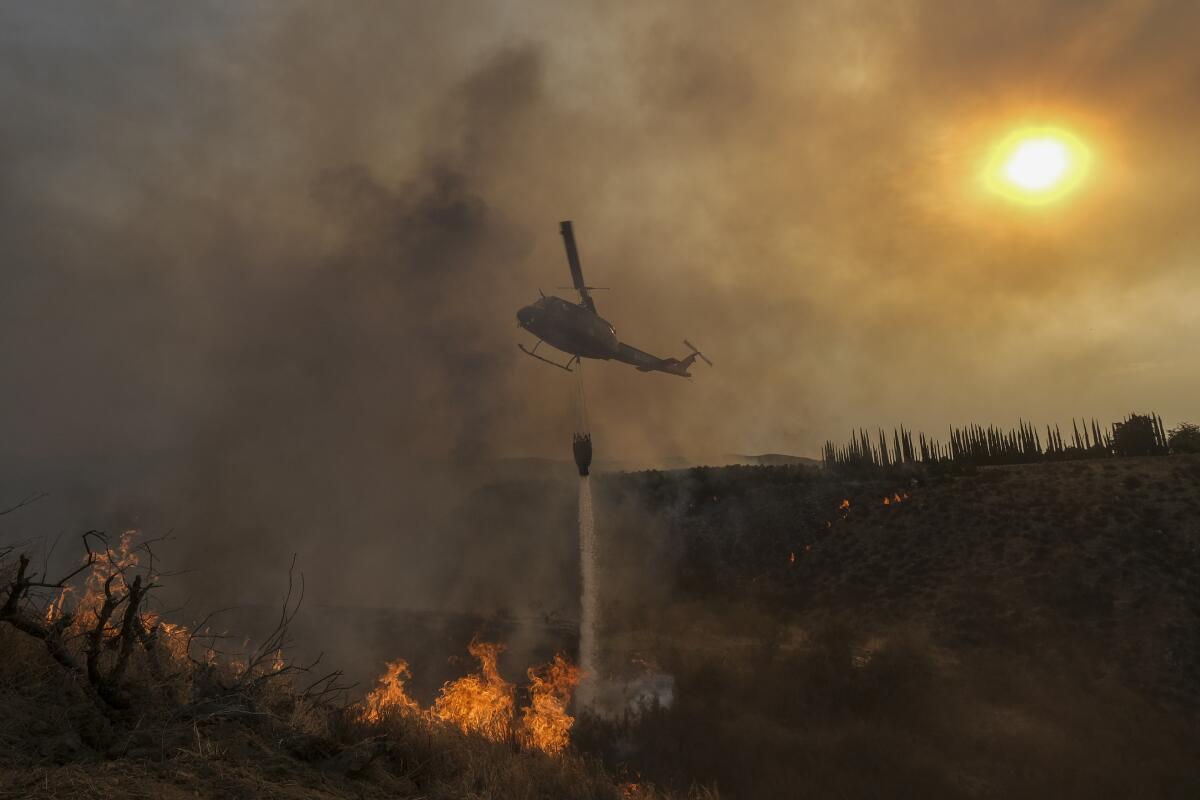 ARCHIVO - Un helicóptero lanza agua sobre el incendio Fairview en una ladera