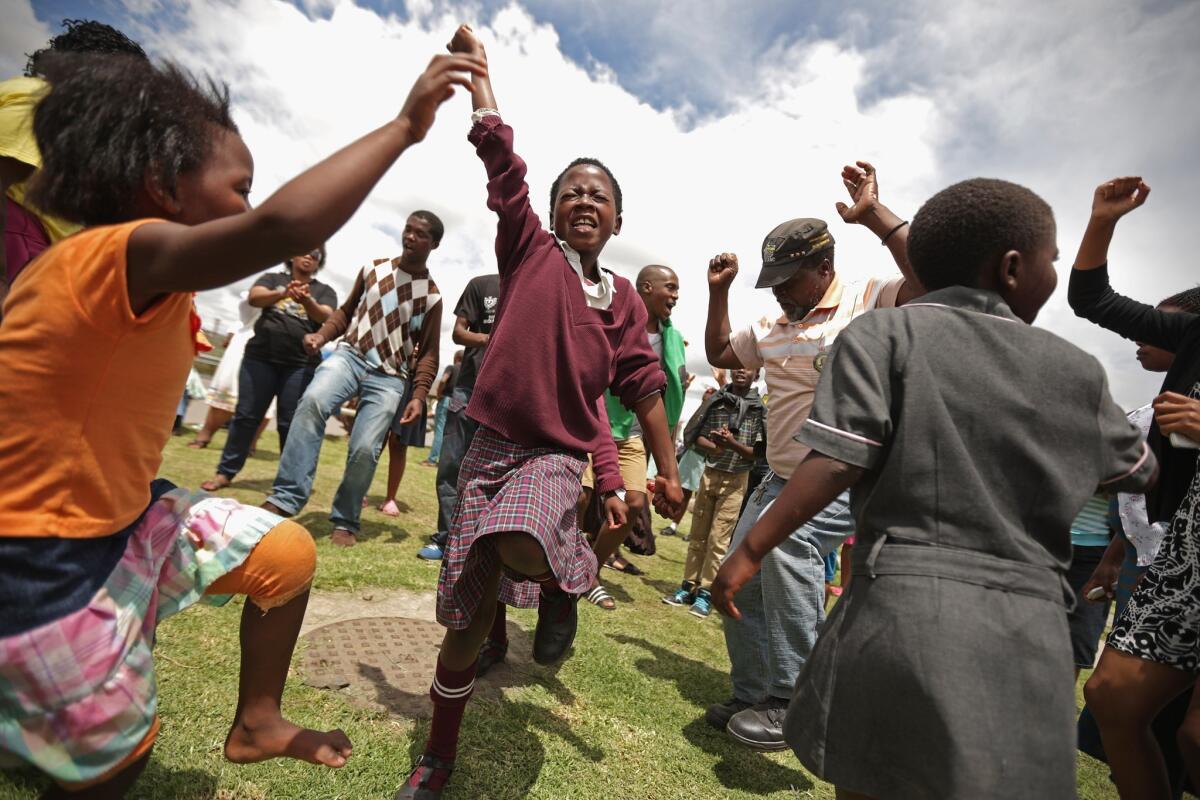 People sing and dance in Mthatha, South Africa, while waiting for the funeral cortege of former South African President Nelson Mandela to pass by on its way to his home village of Qunu.