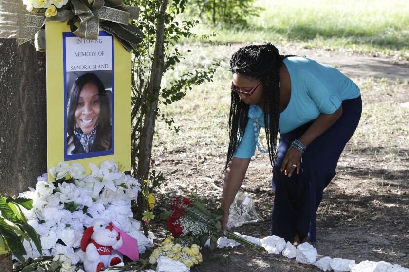 Jeanette Williams places a bouquet of roses at a memorial for Sandra Bland near Prairie View, Texas, on July 21. A newly released dash-cam video documents how a routine traffic stop escalated into a confrontation between a Texas state trooper and Bland, which led to her arrest. Bland was found hanging in her jail cell three days later.