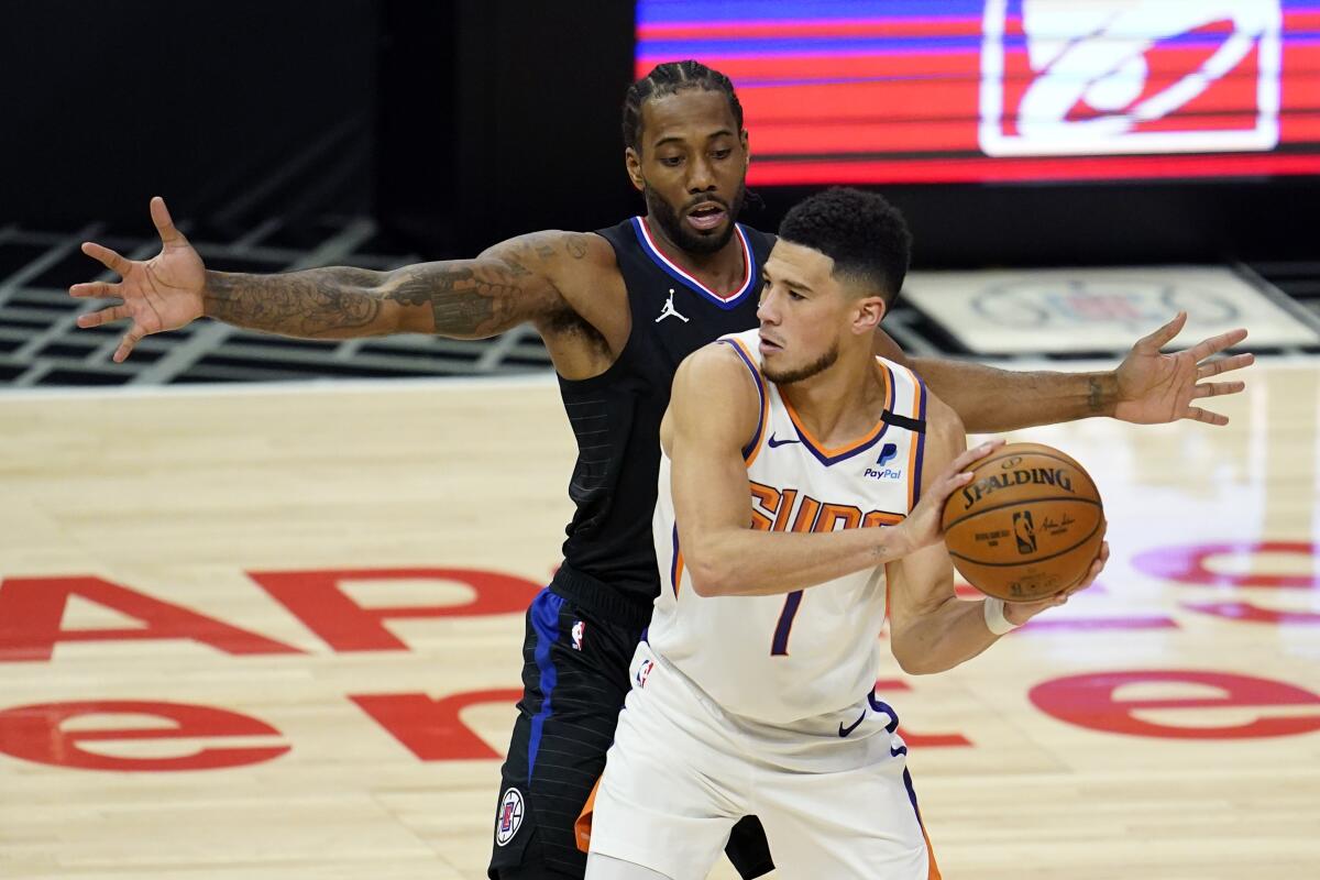 Clippers forward Kawhi Leonard defends Suns guard Devin Booker as he looks to pass.