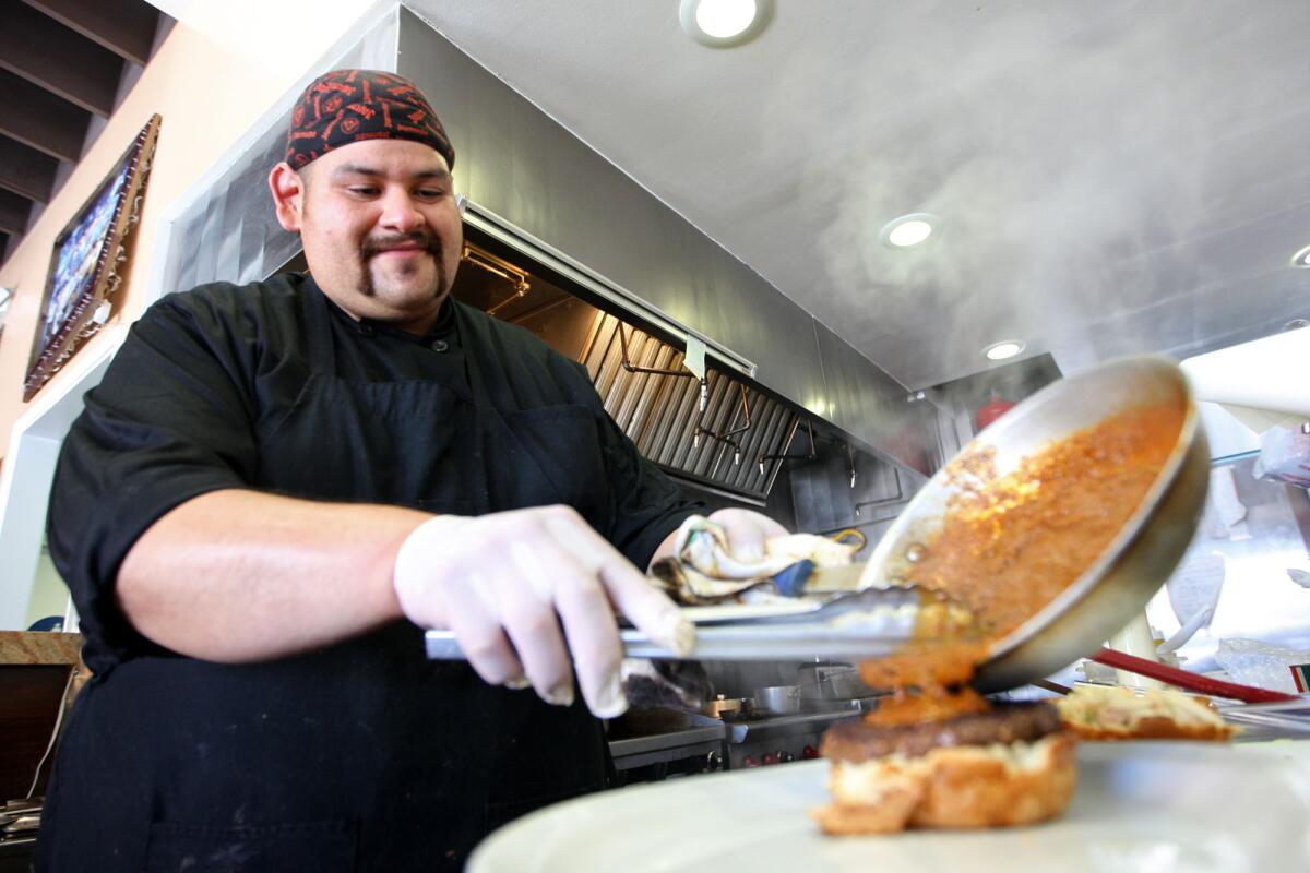 Chef Manny Castro pours chili onto a North Carolina Burger at Sharkey's Bistro in Burbank on Thursday, Sept. 26, 2013.
