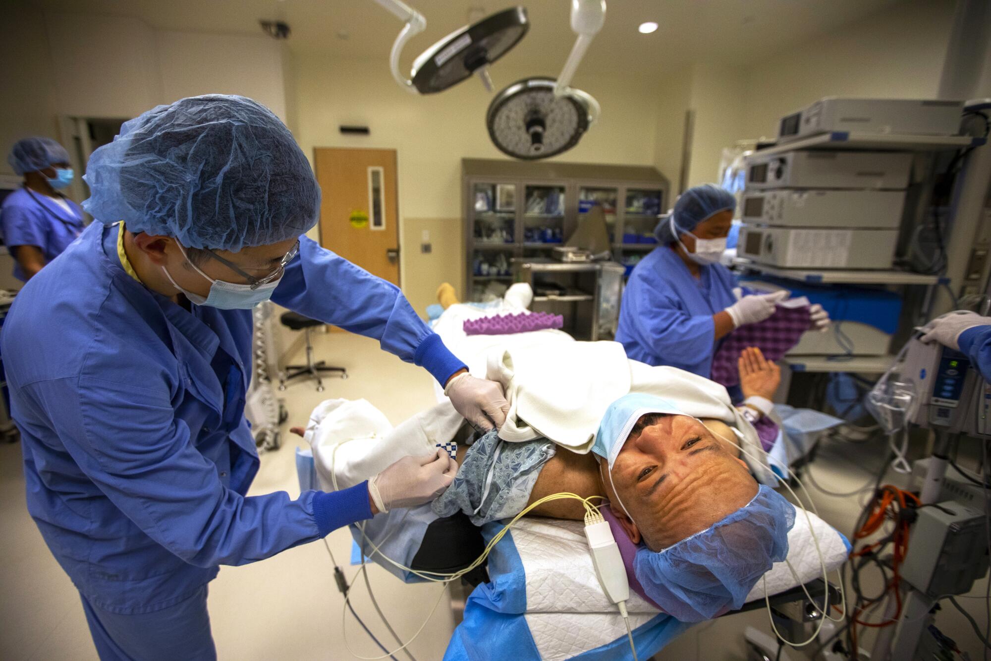 Tony Zamora in the operating room as Dr. J. Shin, anesthesiologist, left, prepares to put him under for surgery.