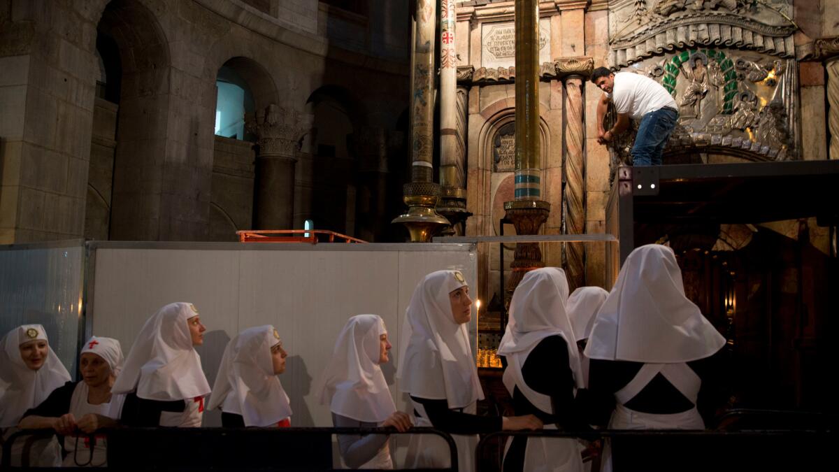 Christian nuns watch as a team of experts begin renovation of Jesus' tomb in the Church of the Holy Sepulchre in Jerusalem's Old City.