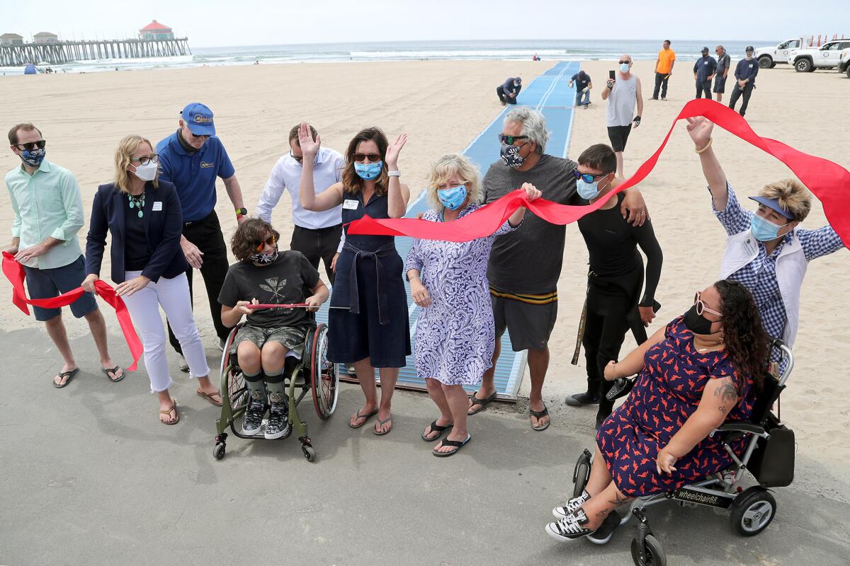 Members of the Huntington Beach City Council celebrate the first Mobi-Mat during a ribbon-cutting ceremony on Wednesday.