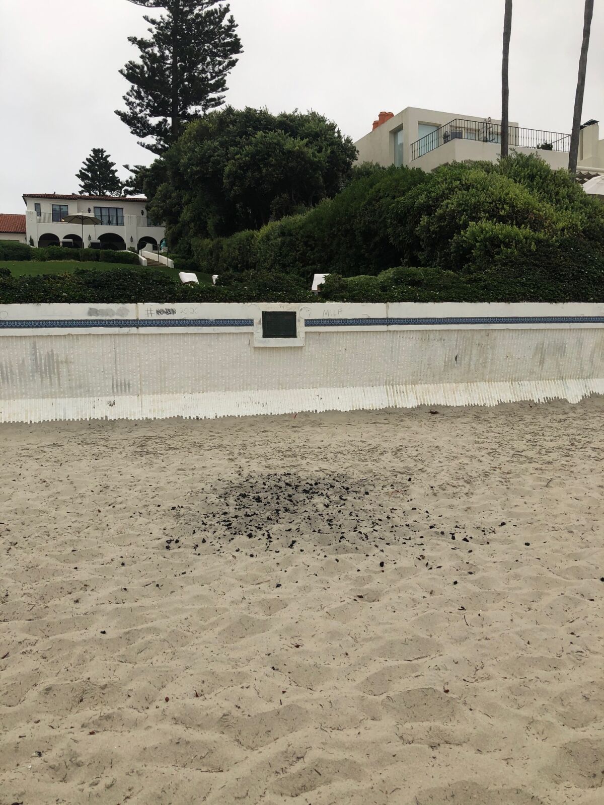 Remnants from a beach fire are scattered in the sand at Marine Street Beach in La Jolla.