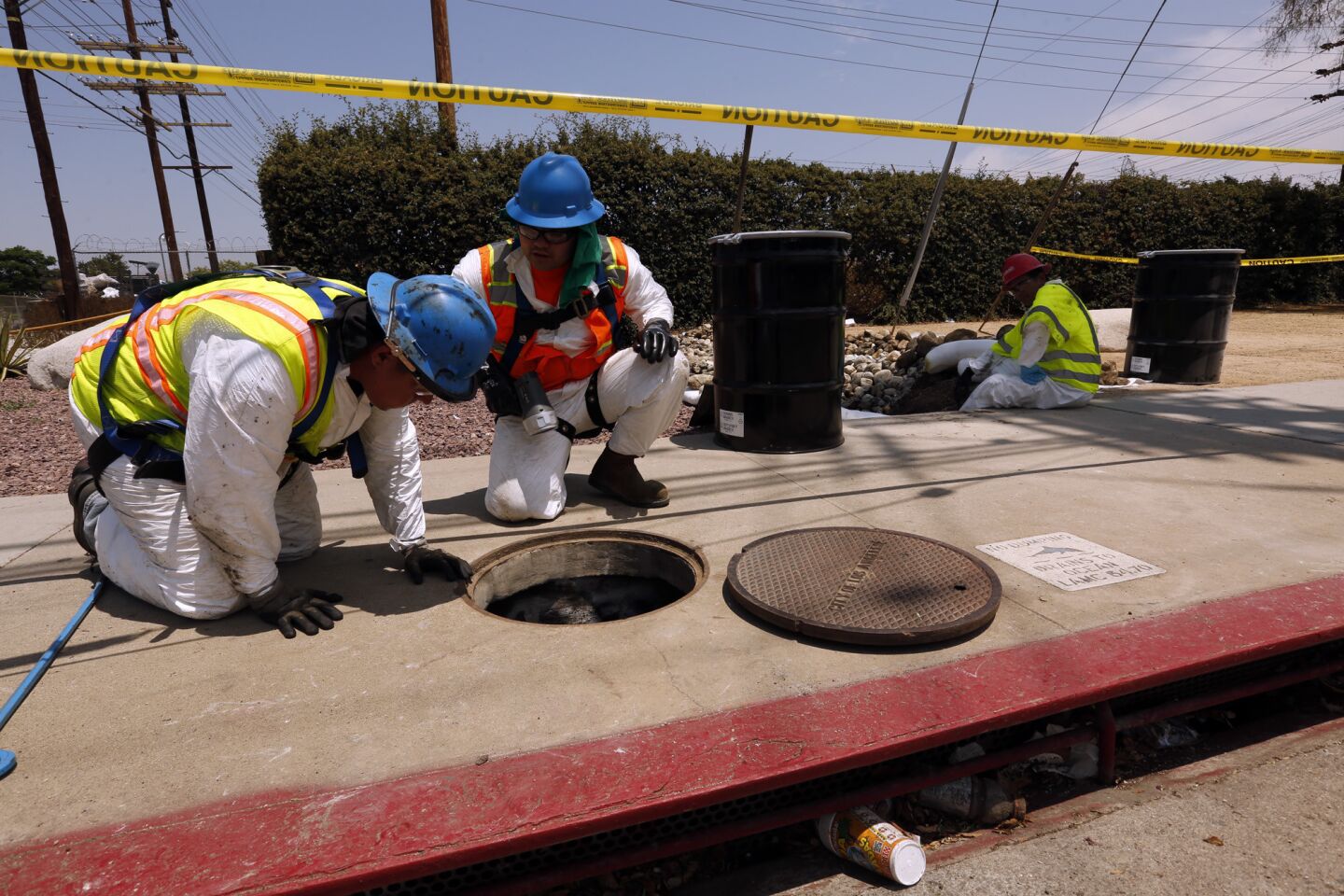 Hazmat workers inspect a storm drain after a Saturday night's explosion at a Department of Water and Power station in Northridge. Thousands of gallons of mineral oil, a coolant, were sent down drains as firefighters used water to douse a burning transformer.