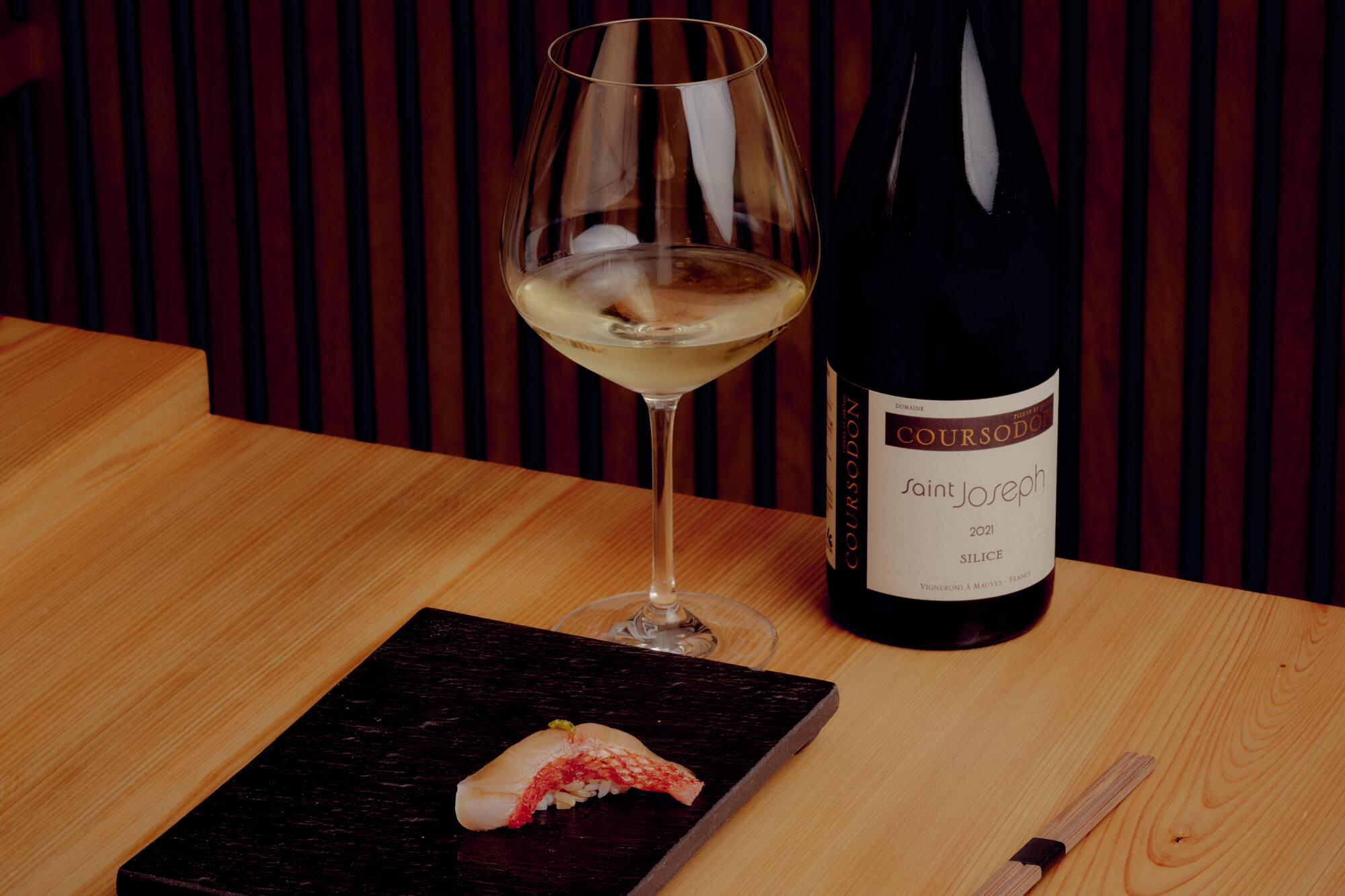 A piece of sushi with a glass and a bottle of French white wine at Sushi Note. 