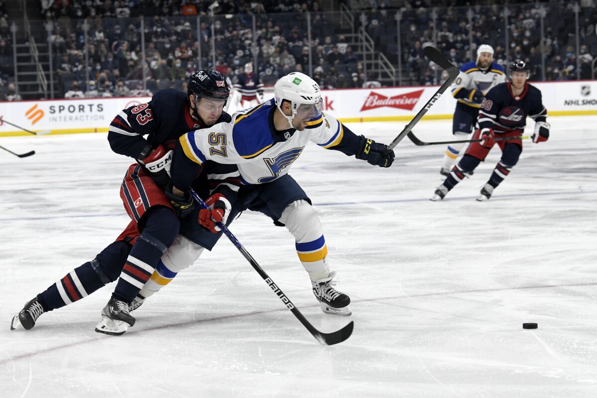 Winnipeg Jets' Kristian Vesalainen (93) tries to skate around St. Louis Blues' David Perron (57) to the puck during the second period of an NHL hockey game Tuesday, Nov. 9, 2021, in Winnipeg, Manitoba. (Fred Greenslade/The Canadian Press via AP)