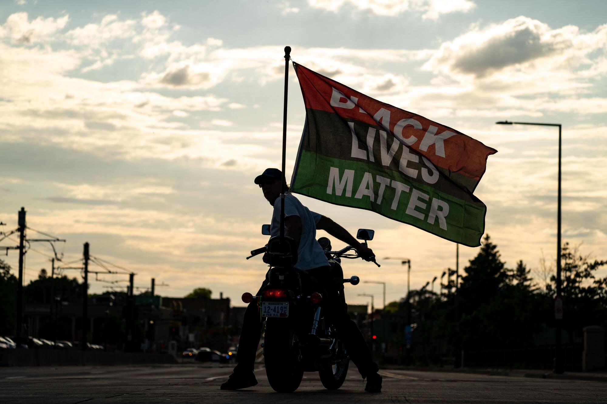 A man on a motorcycle displays a Black Lives Matter flag.