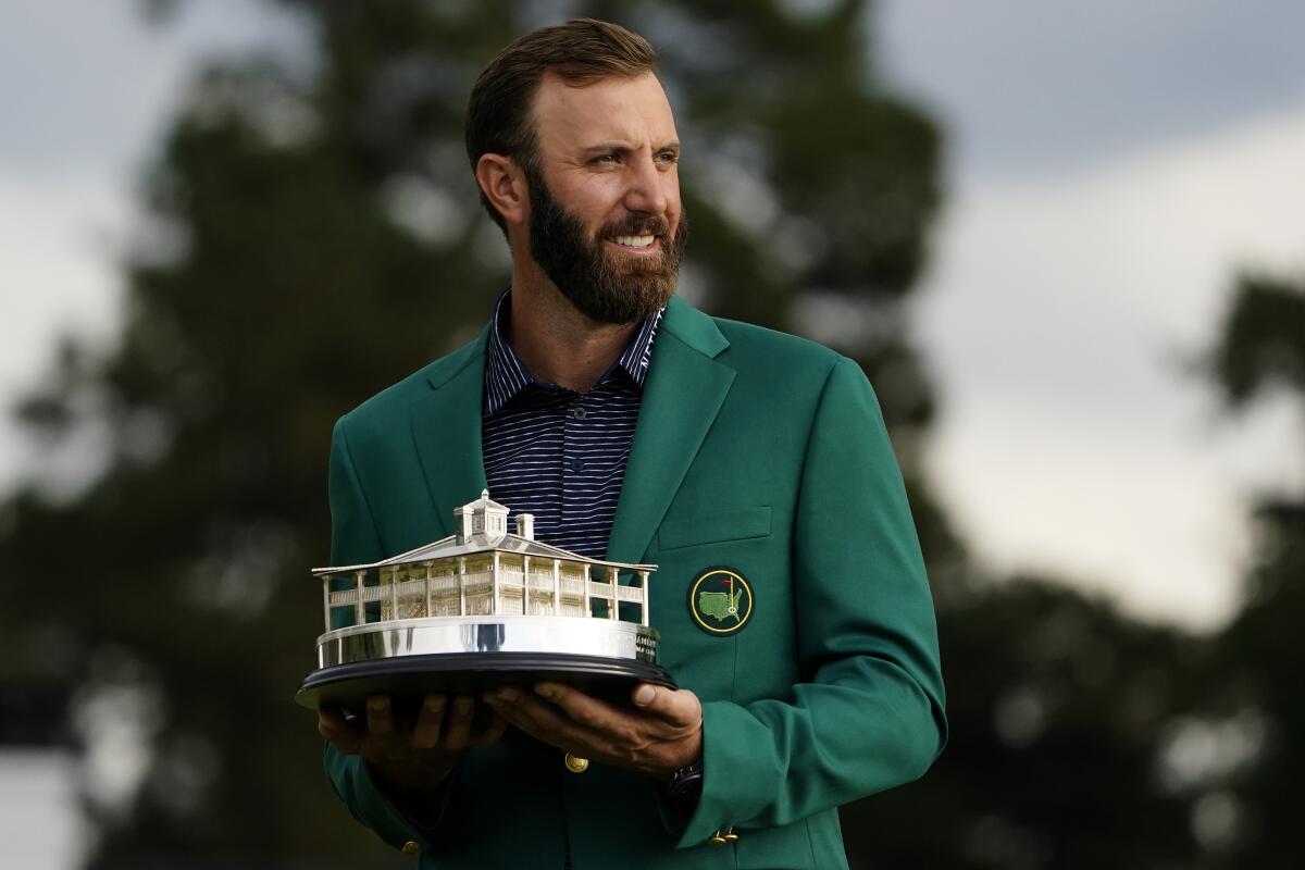 Masters golf champion Dustin Johnson holds the tournament trophy after his victory Sunday.