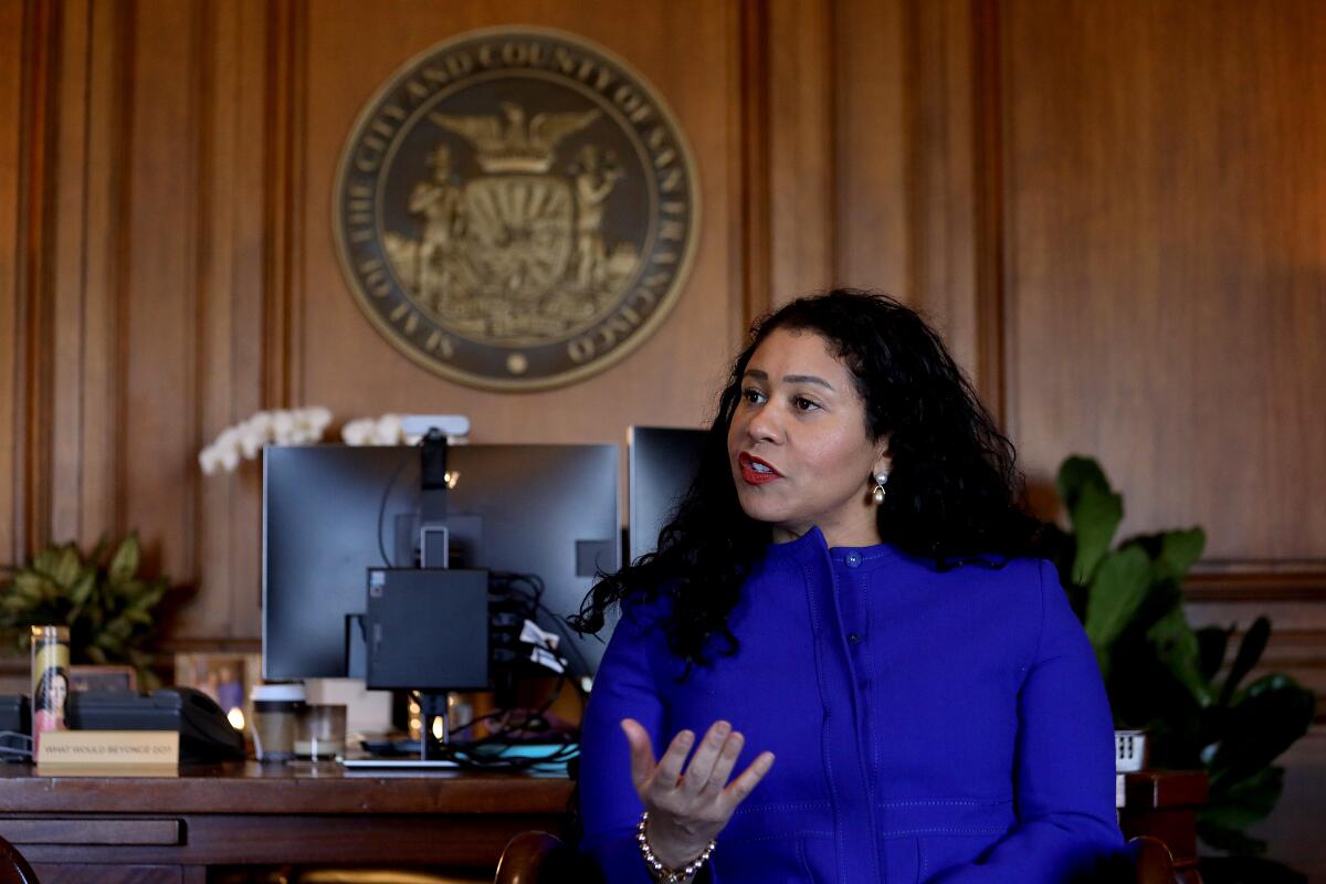 London Breed gestures while speaking in a wood-paneled office at City Hall