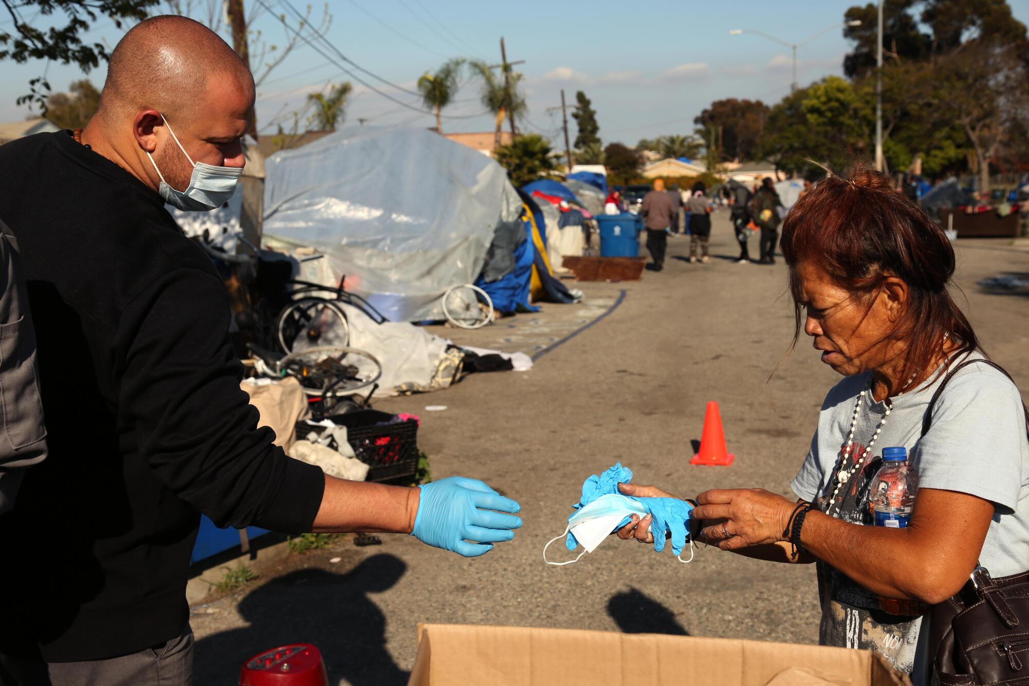 Nonprofit worker Jesse Maroney gives Irma Peralta gloves and a protective mask.
