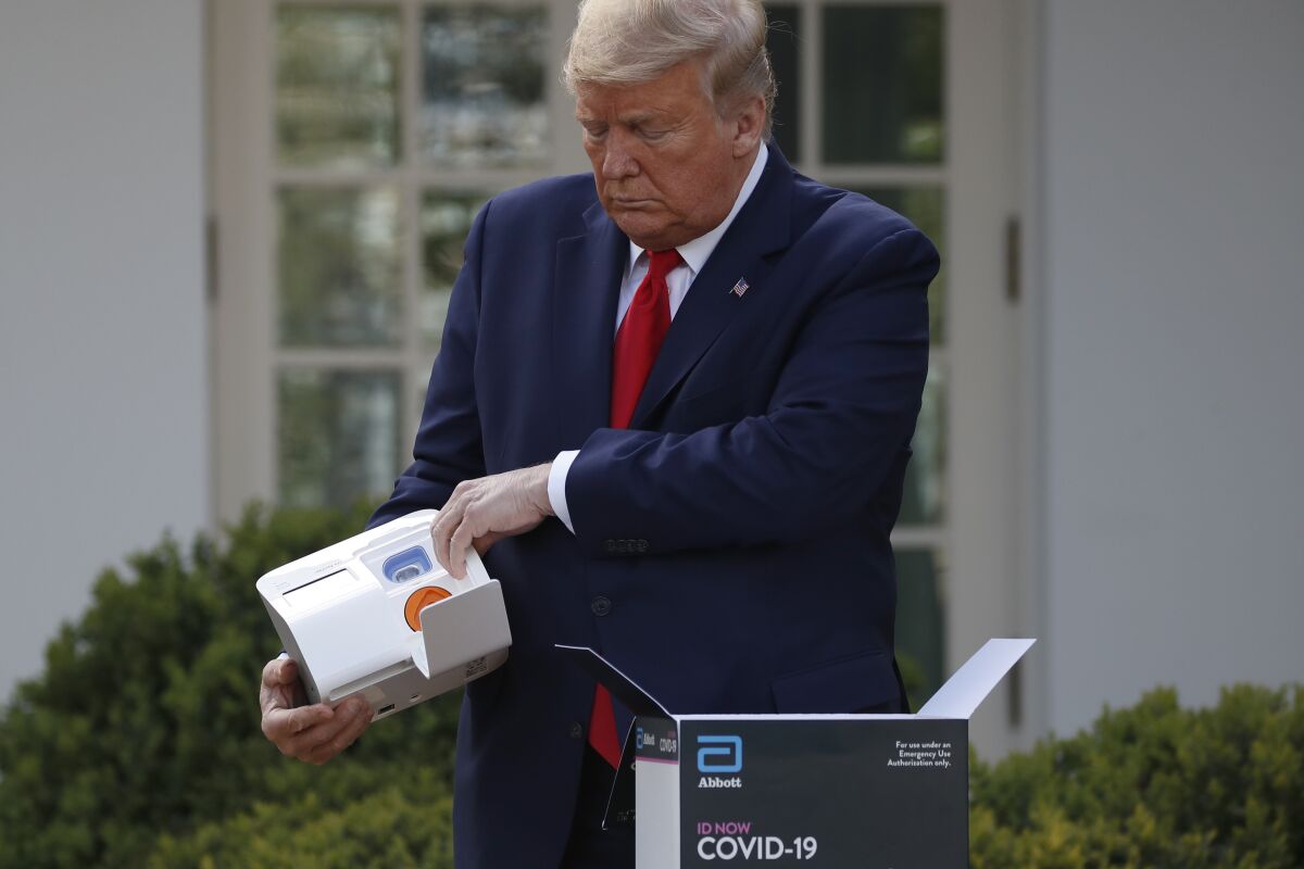 President Trump opens a box containing a five-minute test for COVID-19 from Abbott Laboratories in the Rose Garden of the White House on Monday.