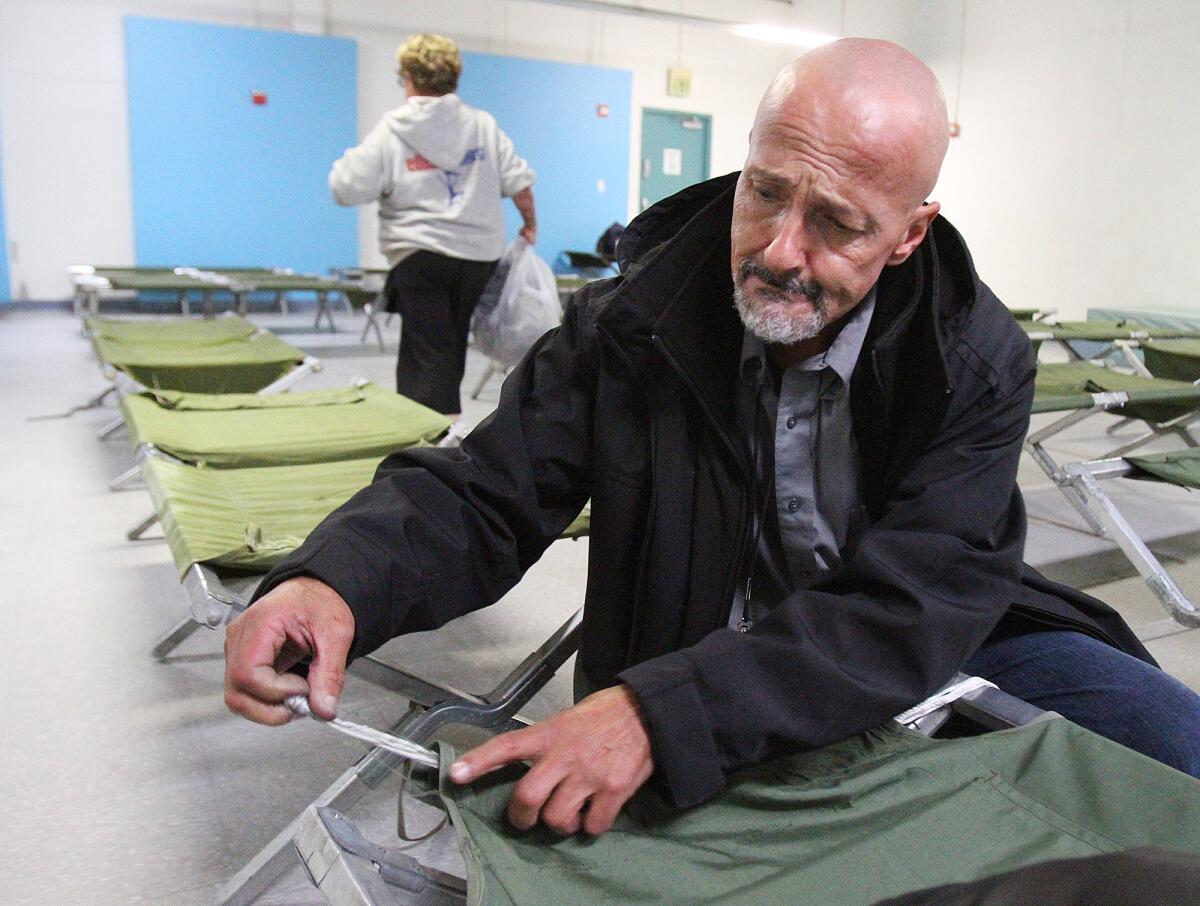 Arthur Morris, who has been homeless about one year, pulls a small rope through the canvas of his cot to create a better sleeping surface at Ascencia in Glendale for the Glendale Winter Shelter Program on Monday, December 2, 2013. He does this because the metal bars that used to be there were once used as a weapon and have since been removed from all the cots making them a little short, and difficult to contain a pillow. Morris' comment was, "Don't complain about it. Figure out a way to solve it," which is why he came up with this solution to his cot, which other people in the room thought was pretty smart. The shelter opened last night for a handful of people, but the 80 bed capacity is expected to fill if it rains in the next couple days. (Tim Berger/Staff Photographer)