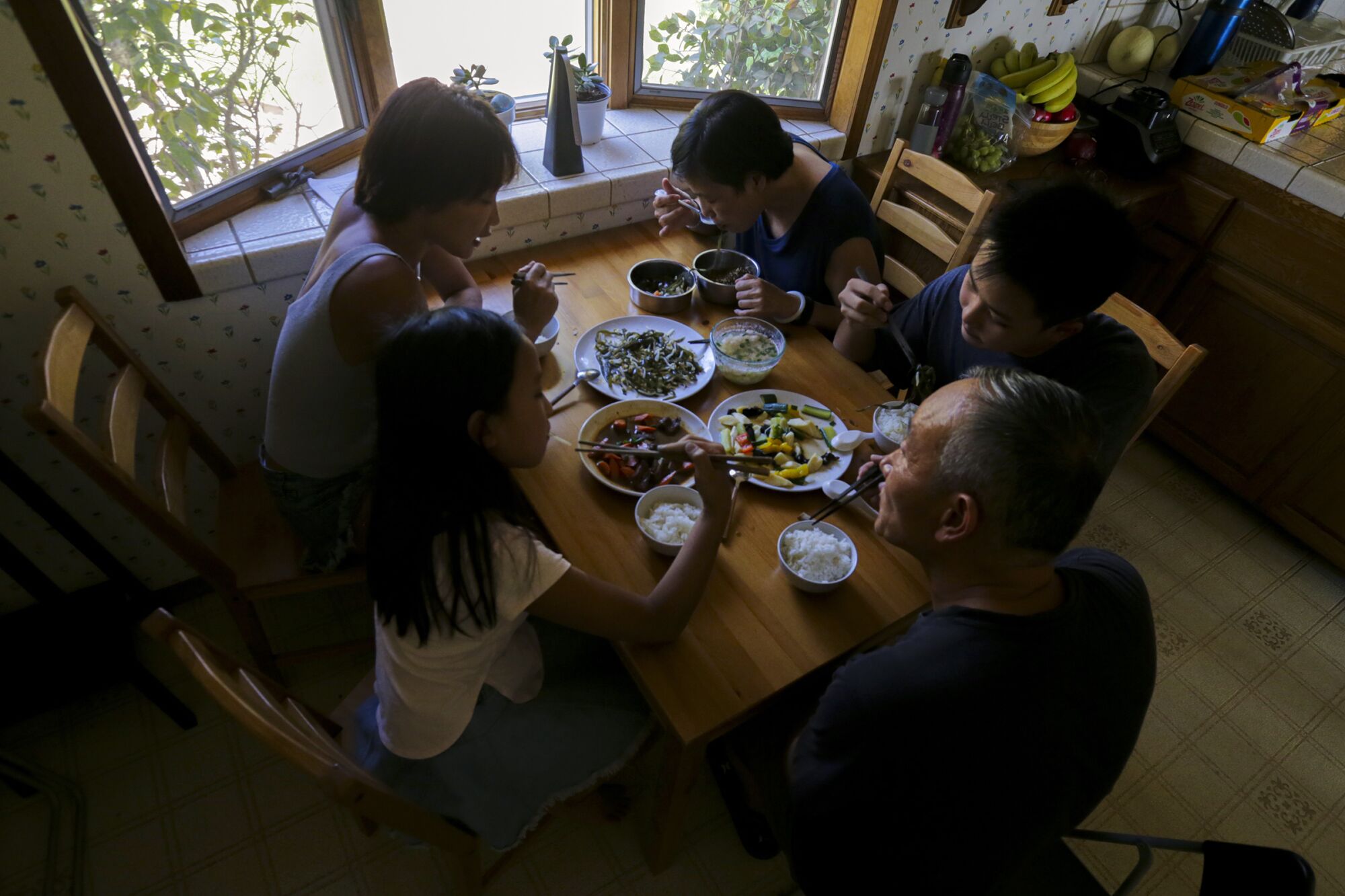 Yi Luo, far left, and her family share a meal at her home in Bradbury.