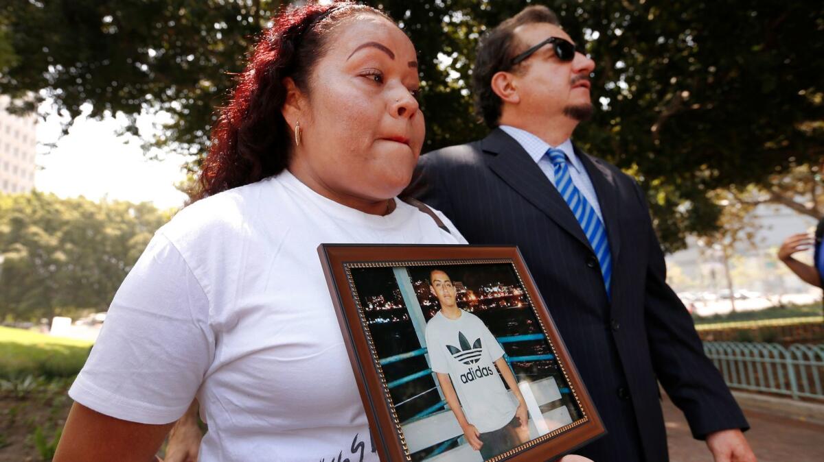 Teresa Dominguez holds a photo of her son, 14-year-old Jesse Romero, next to attorney Humberto Guizar as they hold a news conference to discuss a federal lawsuit filed against the city in the shooting death.