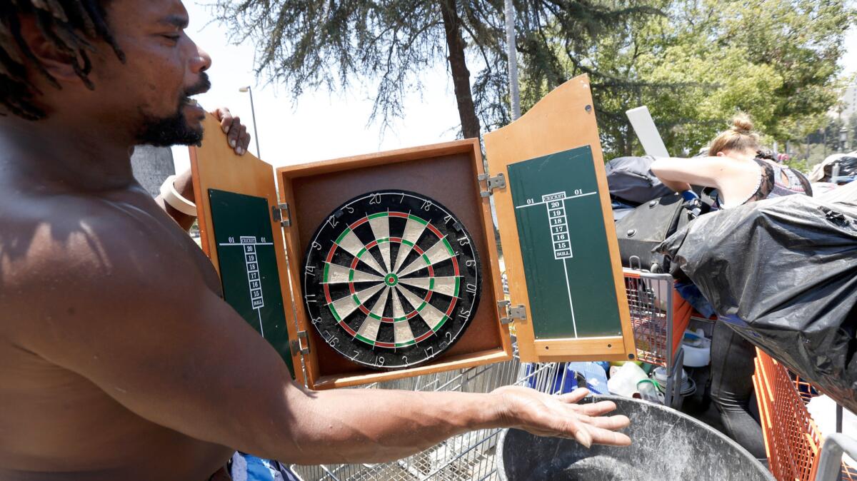Johnny Mayo, 44, who is homeless, shows a dart board that he hopes to sell as a sidewalk vendor in the Westlake neighborhood of Los Angeles.