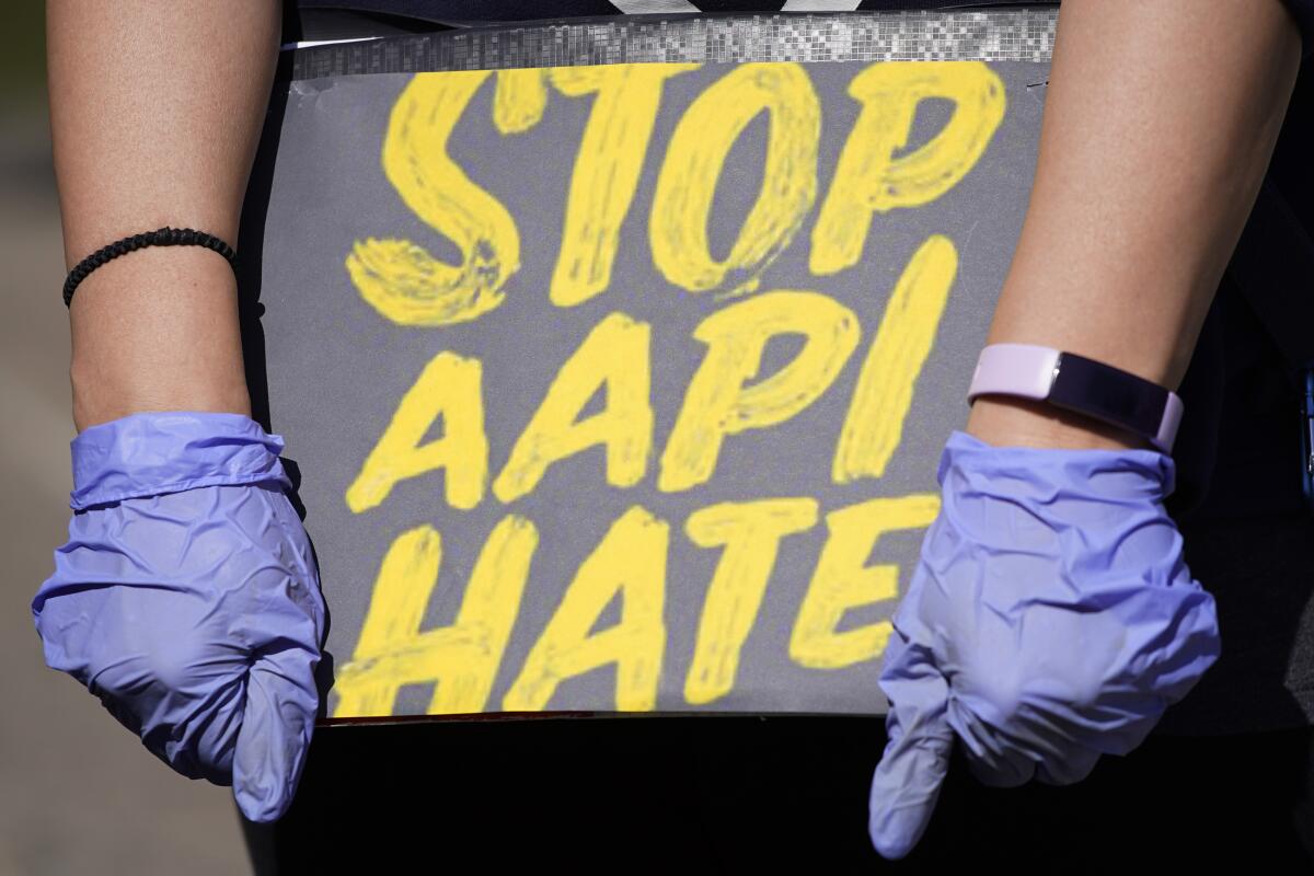 A person holds a sign reading "Stop AAPI Hate."