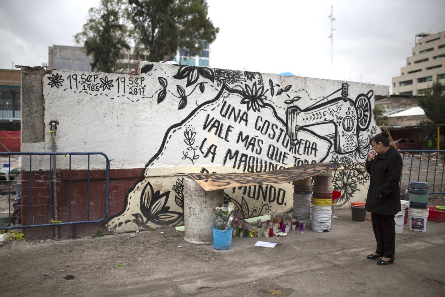 Una mujer ante el último trozo en pie del muro en el número 168 de la calle Bolívar, donde un edificio -con una empresa teconológica y una maquiladora- de cinco plantas se derrumbó, en el barrio de Obrera, Ciudad de México. El mensaje dice "una costurera vale más que toda la maquinaria del mundo".