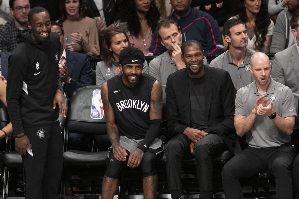 Brooklyn Nets guard Theo Pinson, left, guard Kyrie Irving, center and forward Kevin Durant watch the game action during the second half against the Houston Rockets on Nov. 1, 2019 in New York.