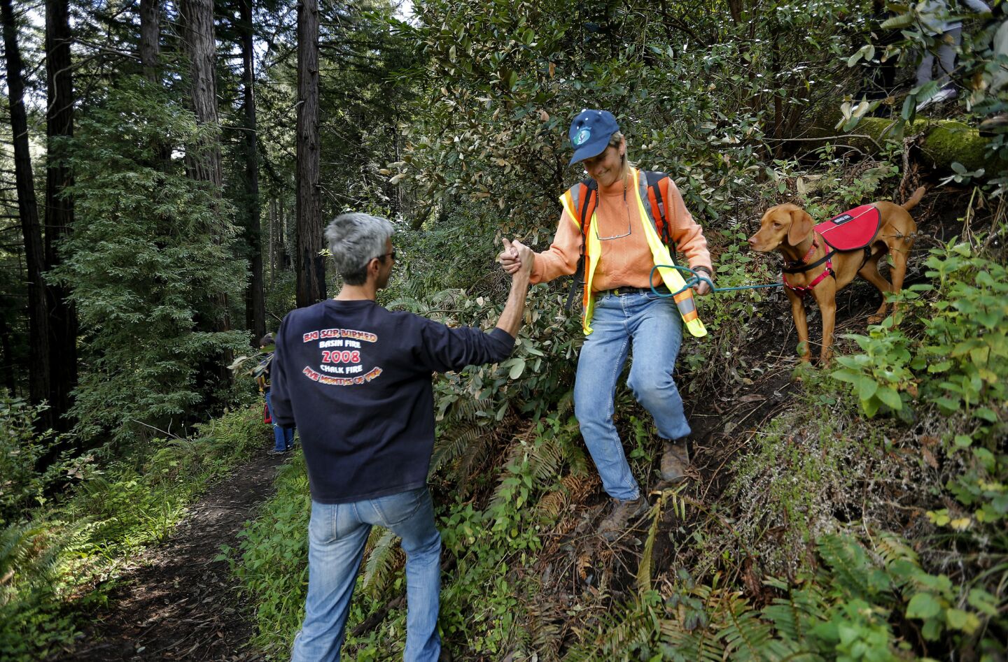 Big Sur resident Carl Swanson, left, gives a helping hand to Carissa Chappellet while navigating a trail inside Pfeiffer Big Sur State Park in order to get to their stranded cars.