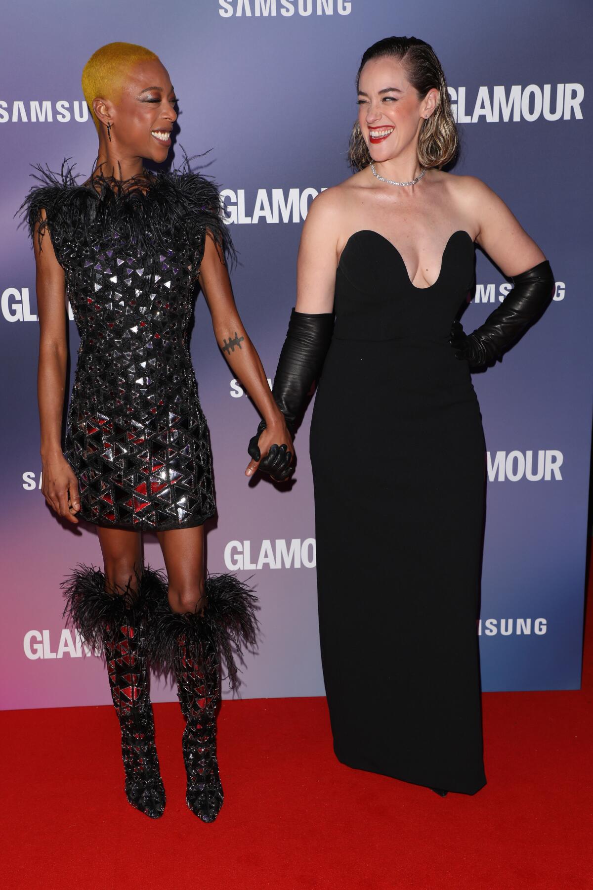 Samira Wiley smiles and holds hands with wife Lauren Morelli on a fancy red carpet