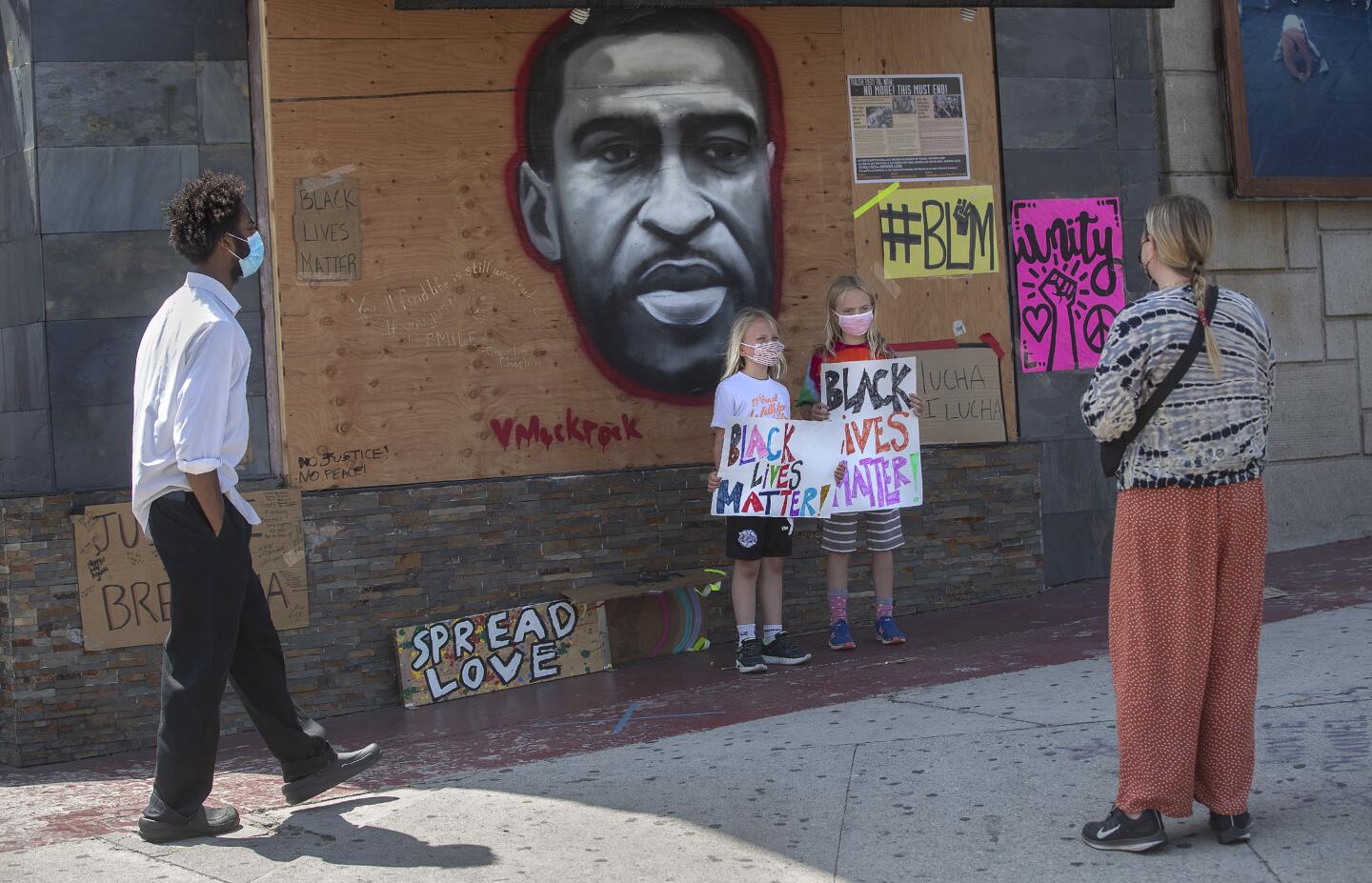Yrsa Bjarkadottir, 7, left, and her sister Chloe Bjarkadottir, 9, poses in front of a George Floyd painting.