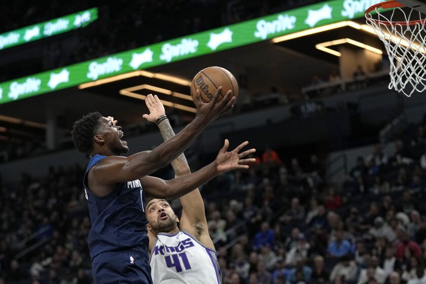Minnesota Timberwolves guard Anthony Edwards, left, goes up to shoot while defended by Sacramento Kings forward Trey Lyles (41) during the first half of an NBA basketball game, Monday, Jan. 30, 2023, in Minneapolis. (AP Photo/Abbie Parr)