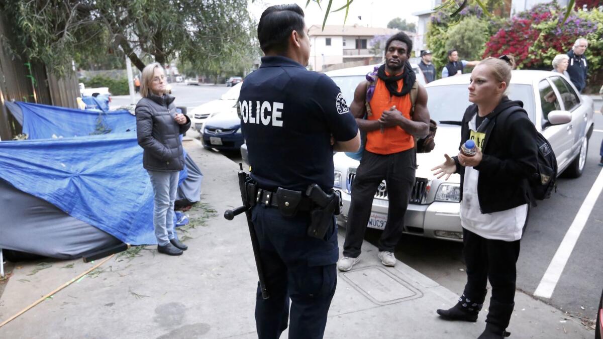 LAPD Officer Eddie Bermudez, center, talks to homeless people on Rose Avenue near 3rd Avenue in Venice.