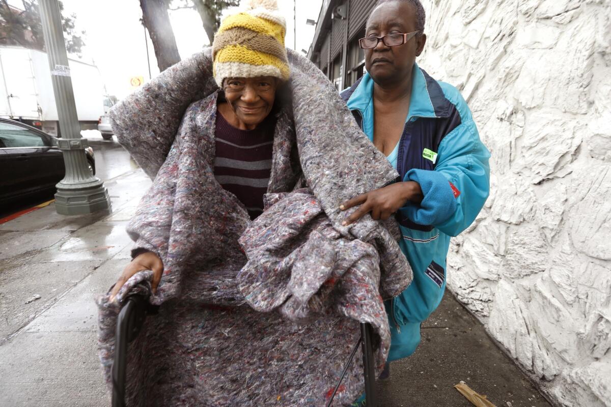 A woman swaddled in blankets is assisted by another woman.