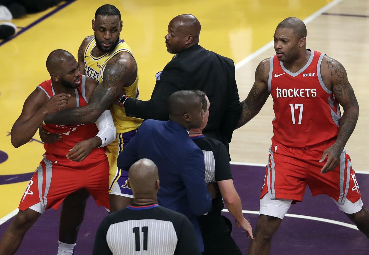 Rockets guard Chris Paul, left, is held back by Lakers forward LeBron James after Paul and Lakers guard Rajon Rondo (not pictured) exchanged punches.