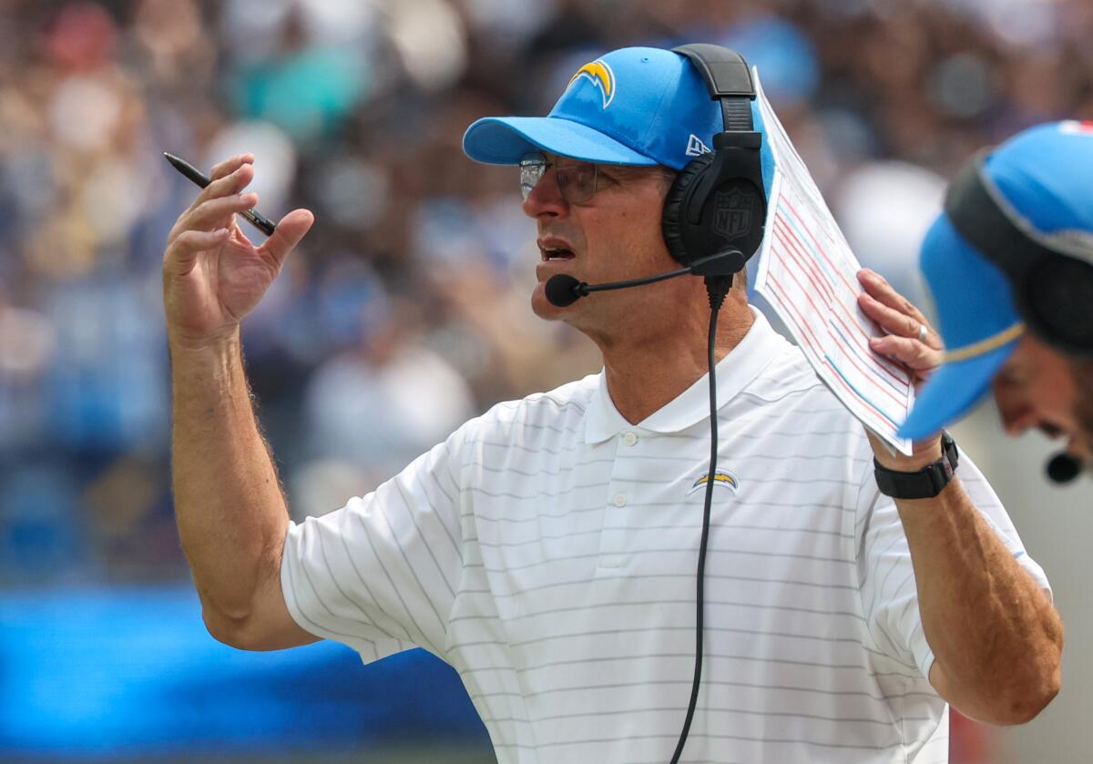 Chargers coach Jim Harbaugh signals from the sideline.