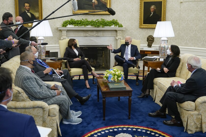 President Biden and Vice President Kamala Harris are shown seated with lawmakers in the Oval Office.