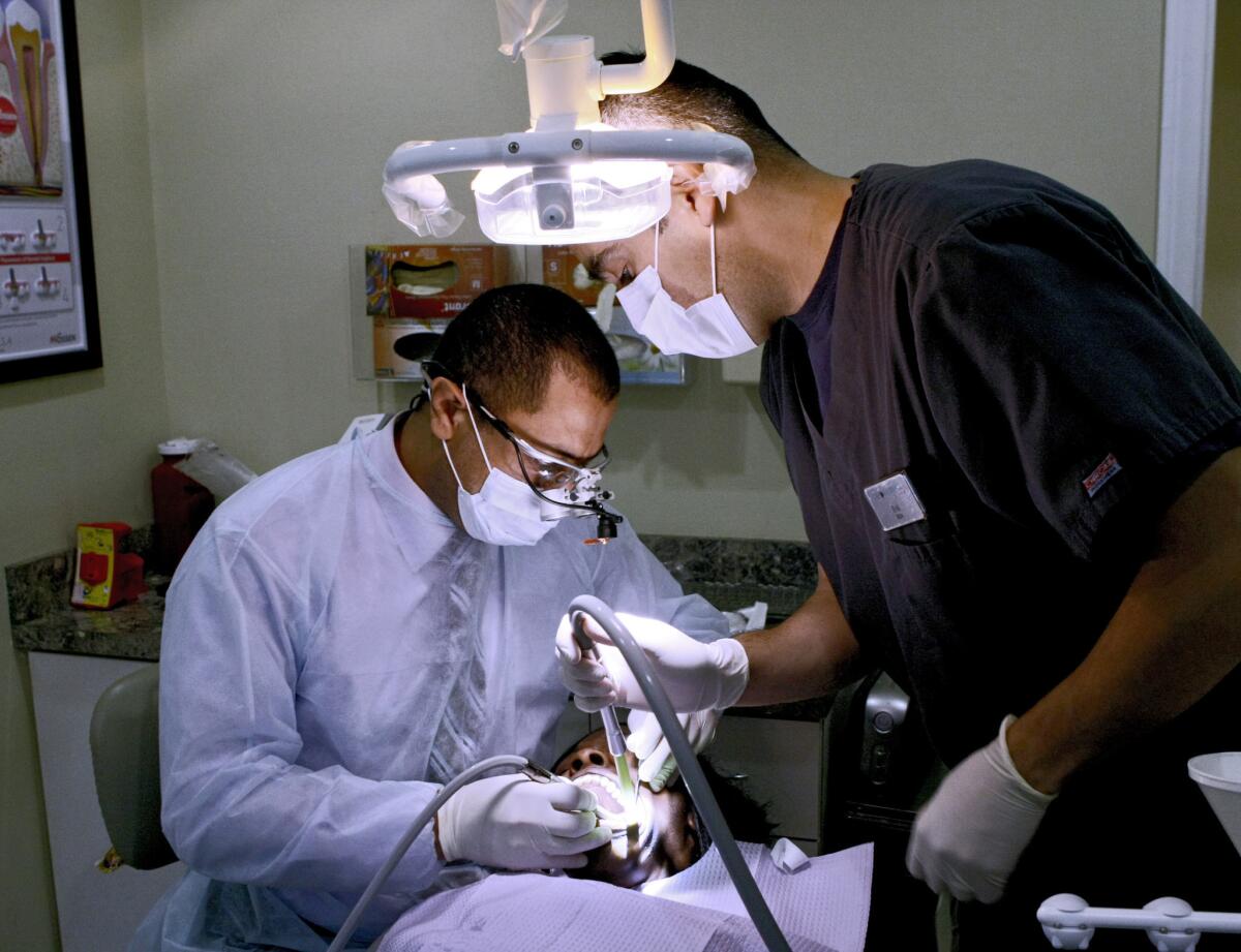 Dr. Ed Bishay, left, works on a patient during the California Dental Group's annual free emergency dental care event on South Glendale Avenue in Glendale on Wednesday, Sept. 25, 2013. Procedures included cleaning, extractions and fillings.