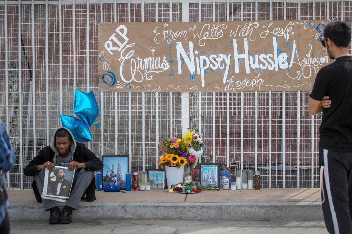 Mekihi Arthur, 15, sits in front of a memorial to Nipsey Hussle outside the Watts Towers in South L.A.