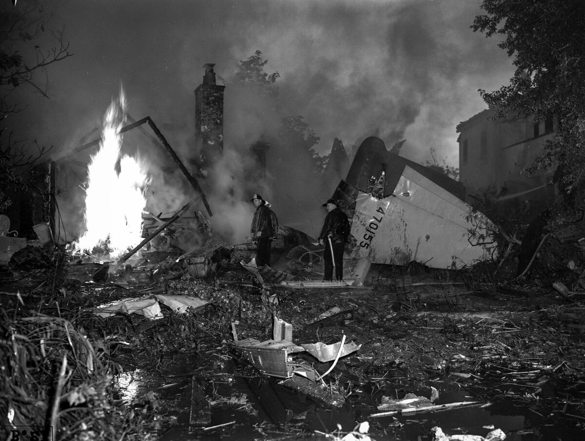 July 7, 1946: Firefighters survey the damage to Lt. Col. Charles A. Meyer's home, which caught fire after Howard Hughes' plane crashed into it.