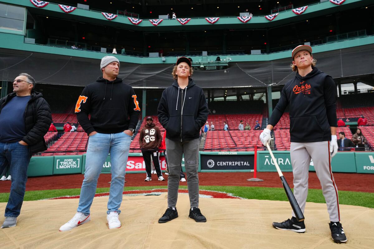 Jackson Holliday of the Baltimore Orioles stands with father Matt Holliday and brother Ethan Holliday on a baseball field
