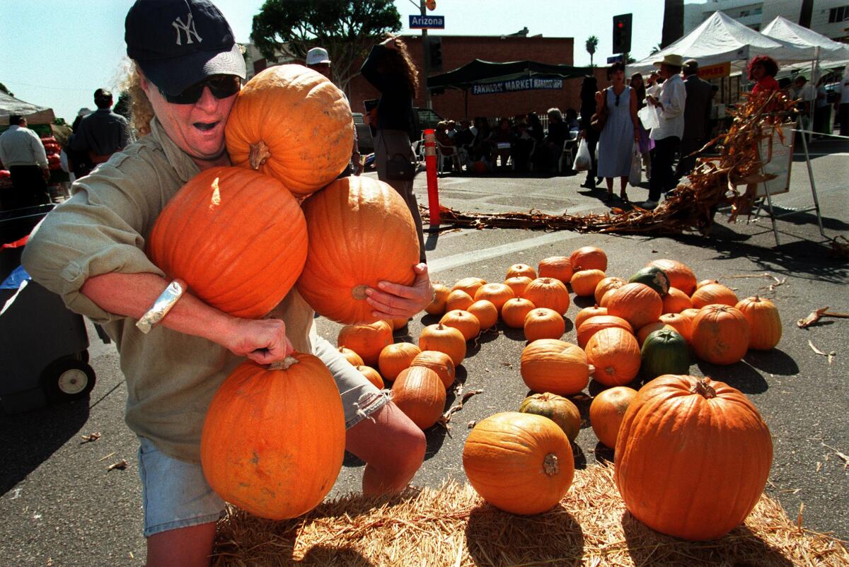A customer tries to carry four pumpkins at once at the Santa Monica farmers market All-You-Can-Carry Pumpkin Patch in 1998.
