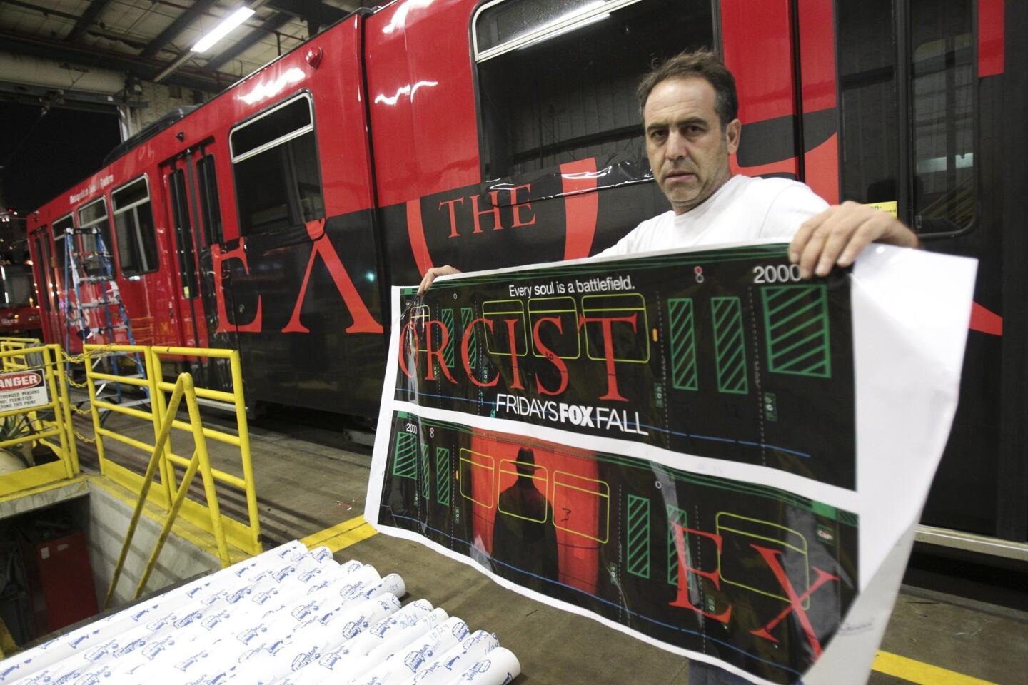Farzad Parvizi shows a scaled down printout of what he and his nephew, who are with Pixel imaging Media, will wrap the trolley car behind him with.