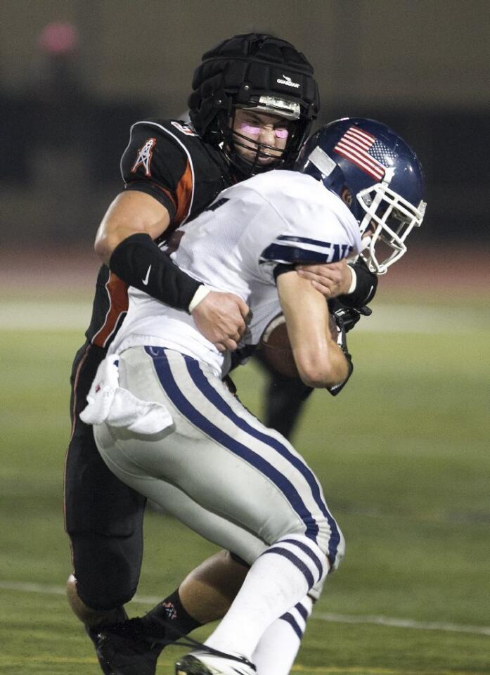 Huntington Beach's Drew Becker stuffs Newport Harbor's Cory Stowell during a game on Friday.