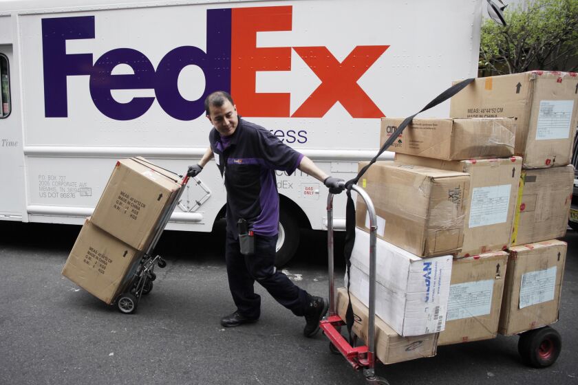 FILE - In this March 22, 2012, file photo, a FedEx driver carts packages in New York. FedEx Corp. reported Wednesday, June 18, 2014, that quarterly profit is up as growth in online shopping boosted its ground-shipping business. The package-delivery company said it earned $730 million in its fiscal fourth quarter, which ended May 31, compared with $303 million a year ago, when write-downs weighed on the results. (AP Photo/Mark Lennihan, File)