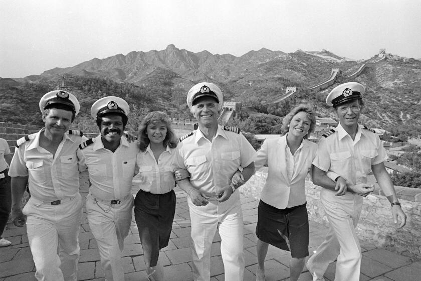 FILE - In this May 30, 1983 file photo the cast of the television series "The Love Boat," at the Great Wall near Beijing, China. From left to right: Fred Grandy, Ted Lange, Jill Whalen, Gavin MacLeod, Lauren Tewes and Bernie Kopell. Gavin MacLeod has died. His nephew told the trade paper Variety that MacLeod died early Saturday, May 29, 2021. (AP Photo/Liu Heung Shing, File)