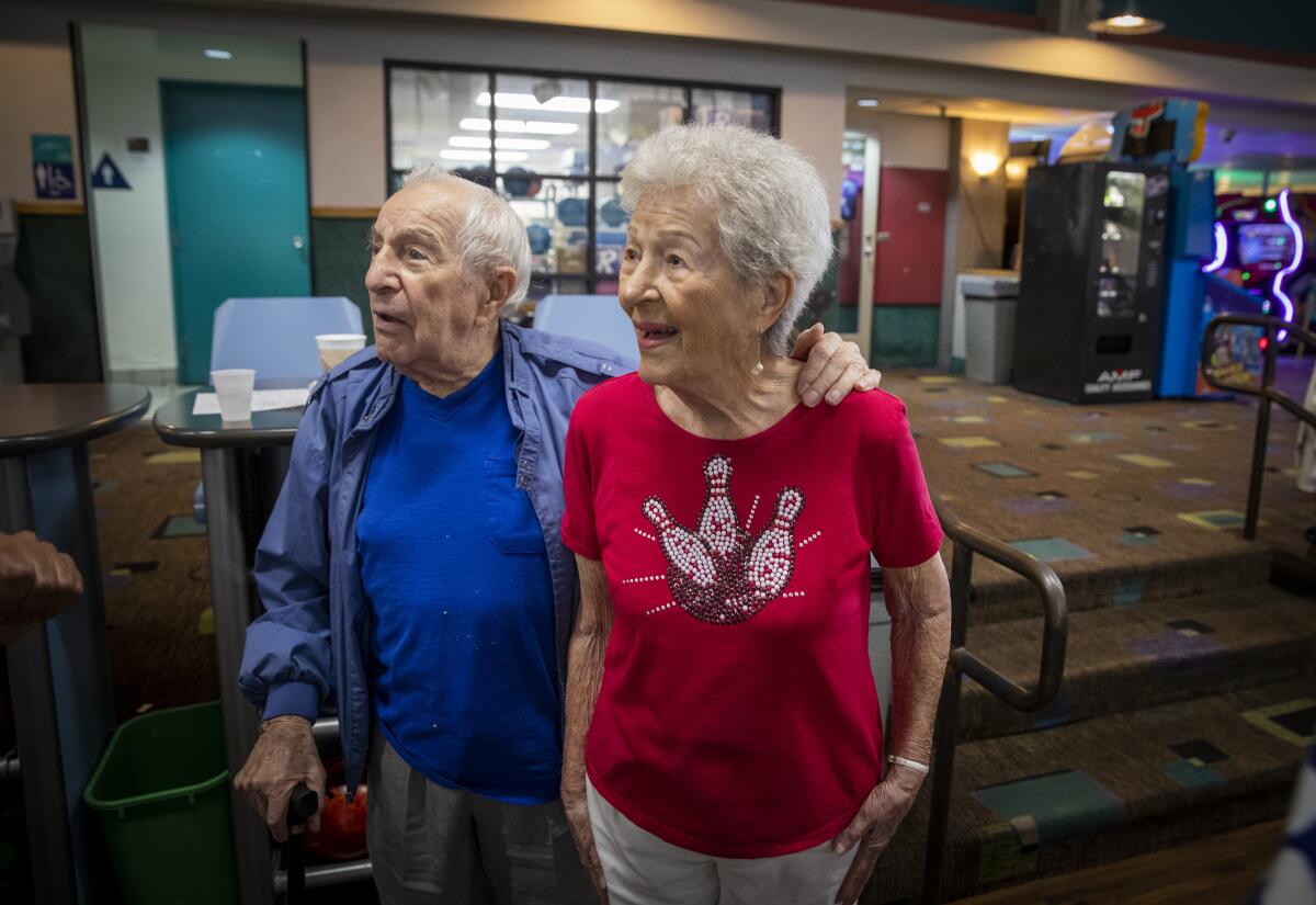 Eddie Huyffer, de 99 años, a la izquierda, y su novia, Lillian Solomon, quien cumple 100 años este 18 de septiembre, pasan el tiempo entre juegos durante la Liga Sénior de Verano de El Segundo, en Gable House Lanes, en Torrance, California.
