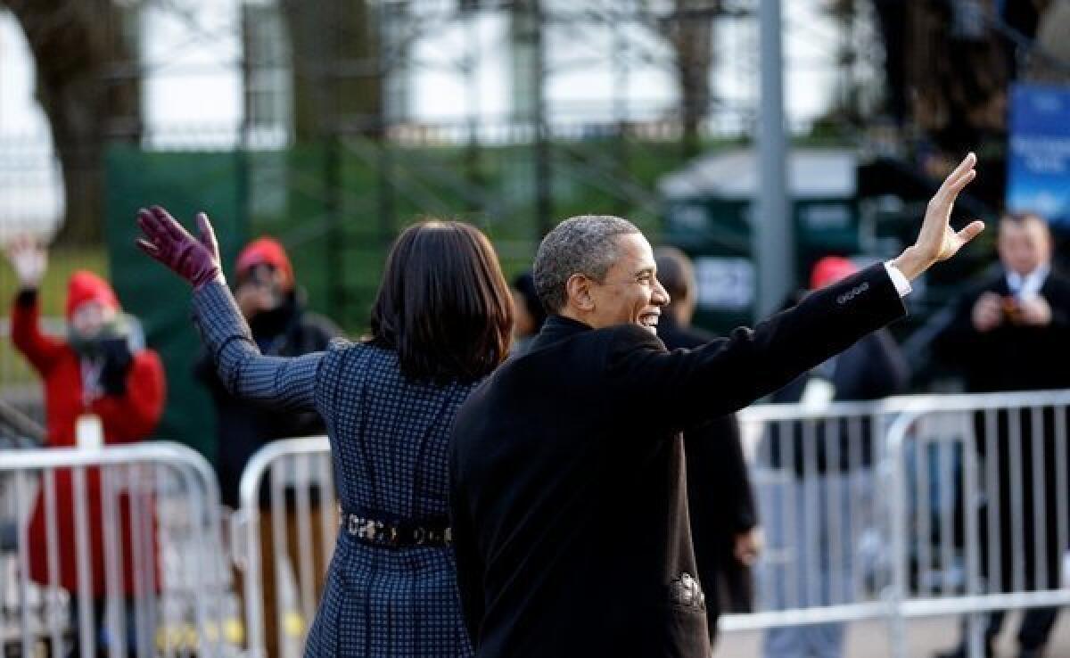 The president and first lady wave to people lining the inaugural parade route Monday in Washington.